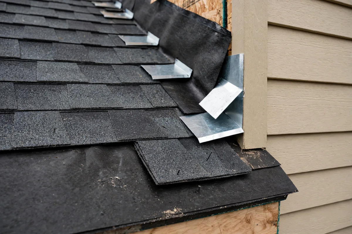 New step flashing being installed where a roof meets a sidewall.